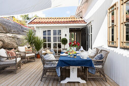 Set table with rattan chairs on wooden terrace with awning