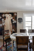 Dining area with antique chairs, large painting with dress motif on wall