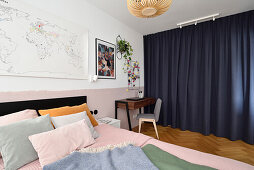 Doppelbett, kleiner Schreibtisch und dunkler Vorhang als Raumteiler im Schlafzimmer