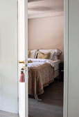 Blick auf Doppelbett mit Tagesdecke durch offene Tür