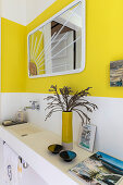 White bathroom with narrow washbasin and yellow accents