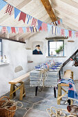 Long table, covered with patchwork runner, pennant strings above in the boathouse