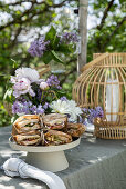 Gedeckter Tisch zu Tea Time mit Fliedern dekoriert im Garten