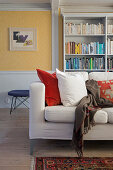 Comfortable sofa, bookshelf behind it in the living room