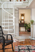 White-painted spiral staircase, antique console and wall mirror in the background