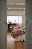 Blick durch geöffnete Schiebetüren ins Schlafzimmer mit freiliegenden Balken