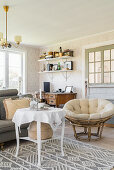 Runder Tisch auf grau-weiß gemustertem Teppich und Sessel im Wohnzimmer im skandinavischen Stil