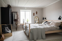 Helles Schlafzimmer mit Doppelbett, antiker Schrank und schwarz-weißem Foto