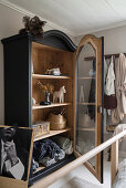 Decorative objects and bed linen in antique wardrobe with glass door