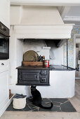 Old cast iron wood-burning stove, cat on stone slabs in front of it