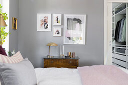 Familienfotos und Druck auf hellgrauer Wand im Schlafzimmer, Blick in begehbare Garderobe