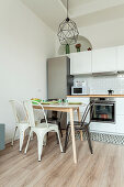 Small dining area with classic chairs in front of white kitchenette
