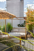 Bed, armchairs, umbrella and planters on the sunny roof terrace