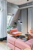 Rosa Sofa und Sessel mit eleganten, schwarzen Beistelltischen und stilvollen Leuchten in offenem Wohnraum