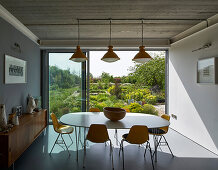Dining area with classic chairs around an oval table with a garden view