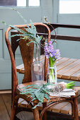 Hyacinths with fruit tree branch and leaf branch in glass bottles on vintage chair