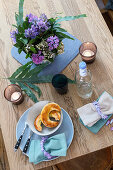 Strauß aus Hyazinthen (Hyacinthus) und Schneeball (Viburnum) in Blechvase und Frühstücksgebäck auf Küchentisch