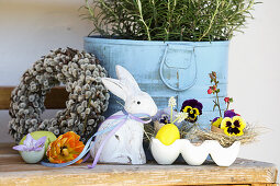 Easter decoration with wreath of pussy willows, Easter bunny and pansies in egg carton
