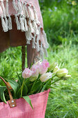 Tasche mit Tulpenstrauß (Tulipa) im Gras