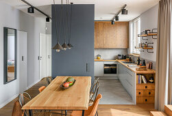 Open kitchen in muted grey tones and natural wood, dining area in the foreground
