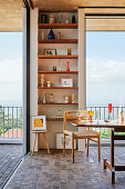 Dining area with retro table and built-in shelves with a view of the sea