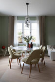Classic table with marble top and upholstered chairs in the dining area with green walls