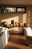 Handcrafted pots on a wooden table and light-colored seating in the living room