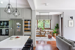 White and grey kitchen with kitchen island, view into dining room and living room