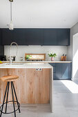 Einbauküche mit dunklen Fronten und Kücheninsel in offenem Wohnraum