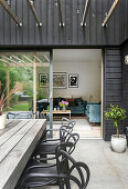 Holztisch mit Designerstühlen auf der Terrasse, Blick ins Wohnzimmer