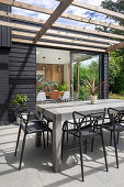 Holztisch mit Designerstühlen auf sonniger Terrasse