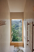 Schmale Dusche mit Mosaikfliesen, Landschaftsblick durch geöffnete Fenstertür