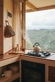 Kleine Küchenzeile mit Gasherd vor Fenster mit Gartenblick