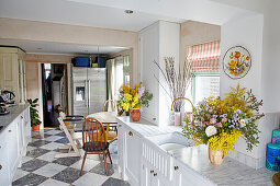 Offene Küche mit weißer Küchenzeile, Edelstahl-Kühlschrank und schwarz-weißen Bodenfliesen