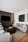 Living room with black brick wall, linen sofas, and dark brown leather coffee table