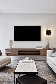 Moderner, in neutralen Tönen gehaltener Wohnbereich mit cremefarbenen Sofas, Couchtischen aus Stein und Metall