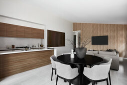 Open plan kitchen and dining area with black column table and grey upholstered chairs
