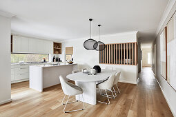 Modern open plan kitchen with coastal style dining area, 80s style column dining table and white upholstered chairs