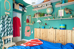 Open shelves, including narrow wooden wardrobe in bedroom with blue walls
