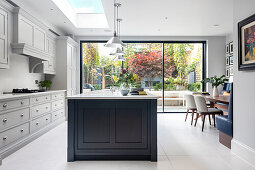 Airy kitchen and dining area with skylight and floor-to-ceiling glass doors to the terrace