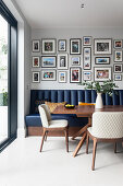Photo gallery above blue faux leather bench seat, walnut dining table and white chairs in the dining area
