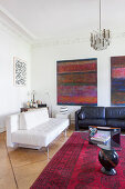 Sitzmöbel in Schwarz und in Weiß, moderne Kunst an der Wand im Altbau-Wohnzimmer