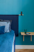 Bett mit Wandbehang als Betthaupt in blauem Schlafzimmer