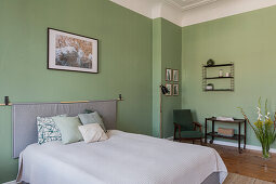 Double bed and sitting area in the bedroom with green walls