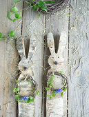 Easter bunny cut out of birch bark with a wreath of birch twigs and grape hyacinths (Muscari), Easter decoration on the terrace