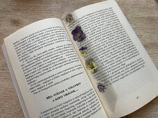 DIY-Lesezeichen aus gepressten Stiefmütterchen in Folie laminiert, zwischen Buchseiten