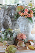 Autumn decoration with bust of a woman, foliage, ornamental apples, pumpkin and roots