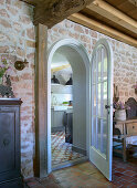 View from the living room with natural stone wall through an open arched door into the kitchen