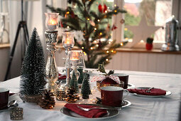 Weihnachtlich gedeckter Tisch mit rotem Kaffeegeschirr und Tannenbäumchen