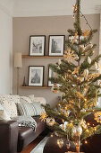 Weihnachtsbaum mit Strohsternen und goldenen Kugeln im Wohnzimmer